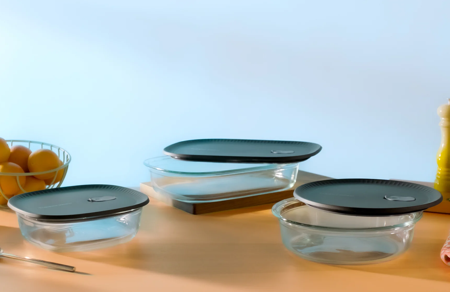 Set of glass food storage containers with black lids on a kitchen counter