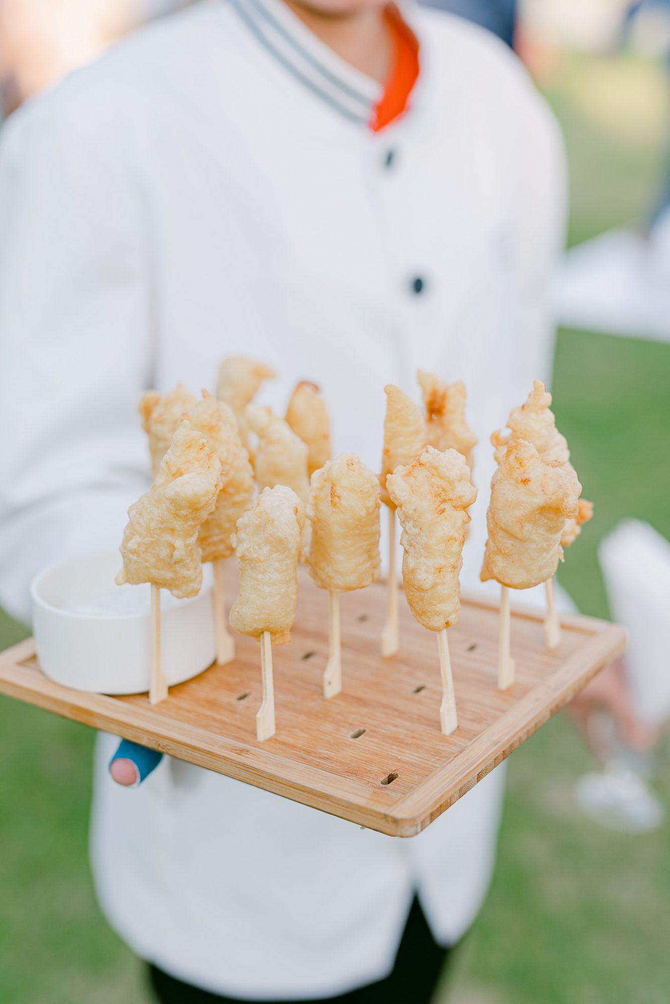 server holding wooden platter of food on sticks
