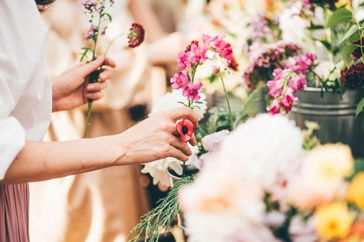 Hands arranging flowers at a market or shop with colorful blooms in focus