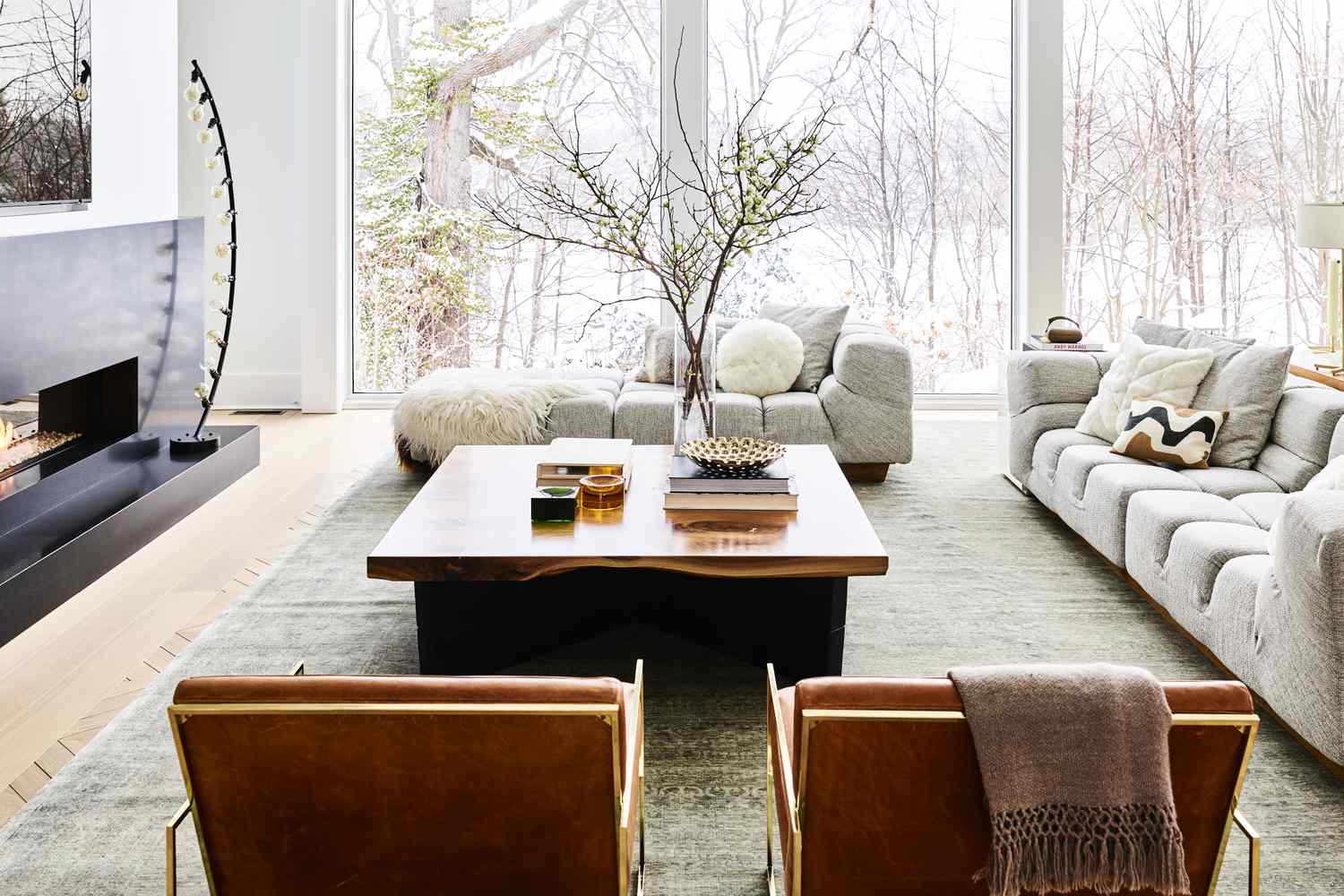 A contemporary living room with large windows a wooden coffee table and modern furniture