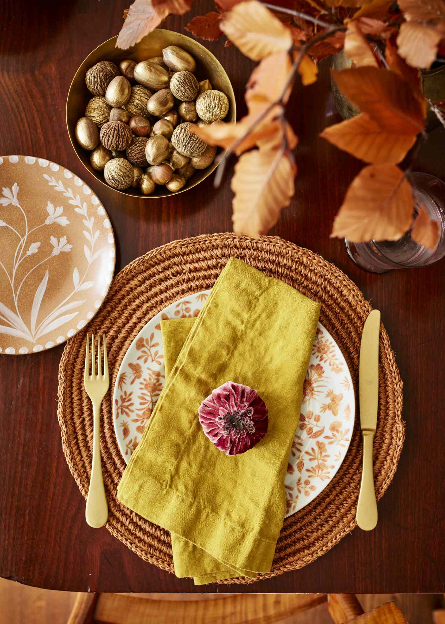 Table setting with a plate cutlery napkin and decorative details including nuts and leaves