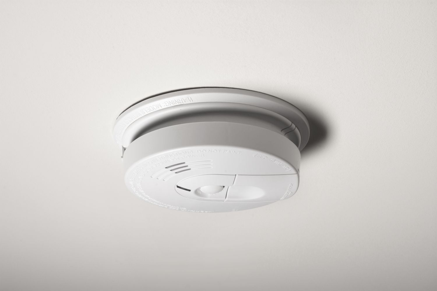 A smoke detector on the ceiling of a home.