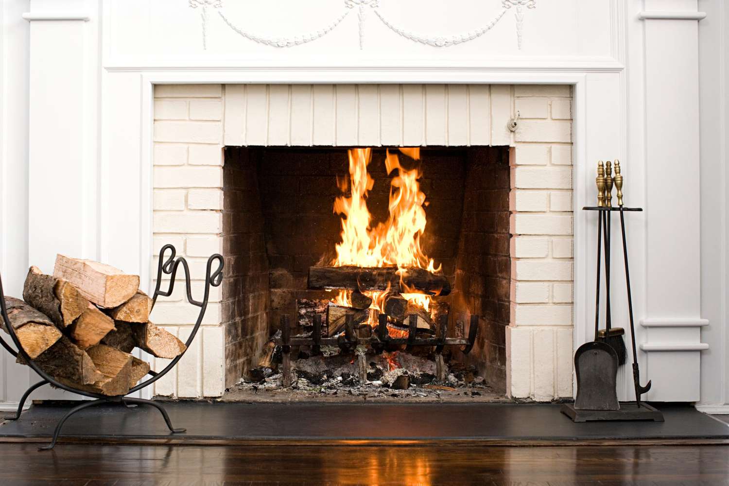 Brick fireplace lit with wood and hardwood flooring