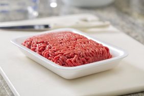 Packaged ground beef on a tray on a cutting board