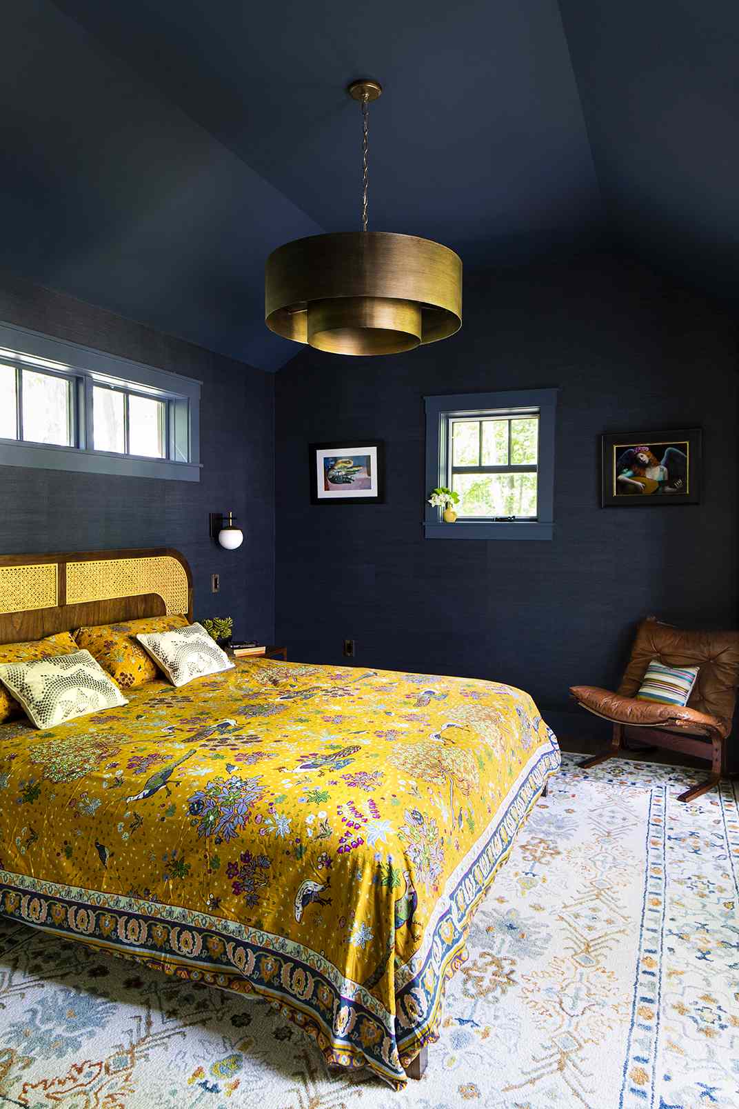 A bedroom featuring a bed with a patterned quilt a decorative chandelier and blue walls