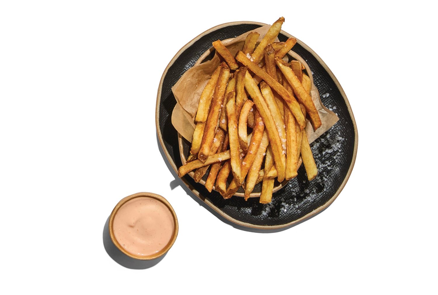 A plate of French fries with a side of dipping sauce