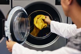 Person loading a washing machine with a garment