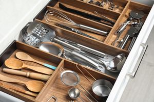 Drawer with kitchen utensils neatly organized in compartments includes spoons tools and measuring cups