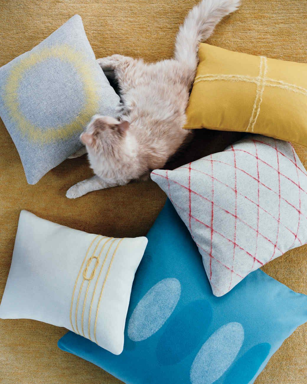colorful felt pillows surrounding a lounging cat
