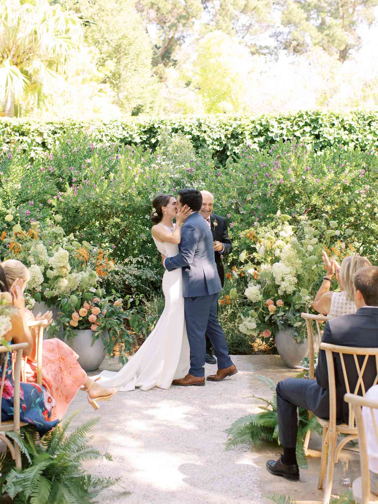 wedding ceremony kiss with floral and greenery backdrop