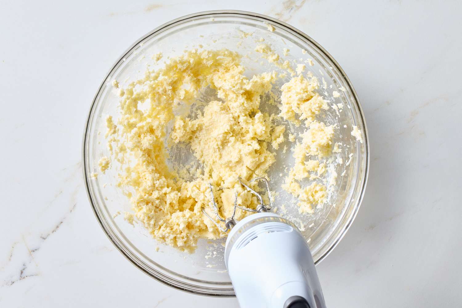 A bowl containing a mixture being prepared with an electric hand mixer visible