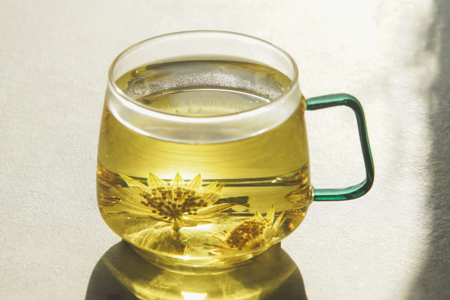 Glass mug of herbal tea with floating flower infusions