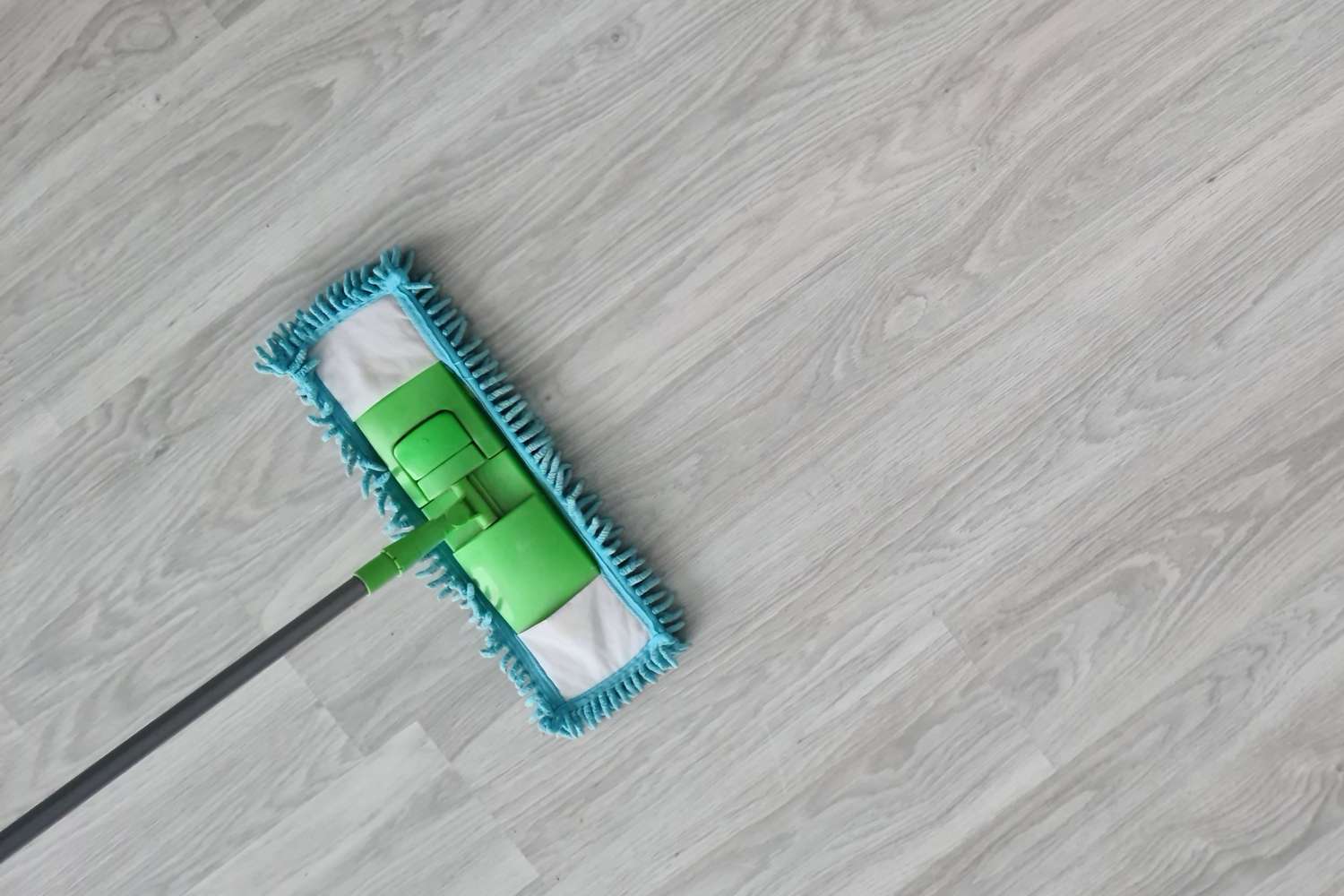 A mop cleaning a light wooden floor