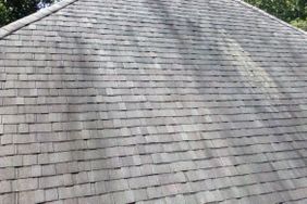 Closeup of a roof with visible discoloration on the shingles possibly caused by the growth of algae or lichen
