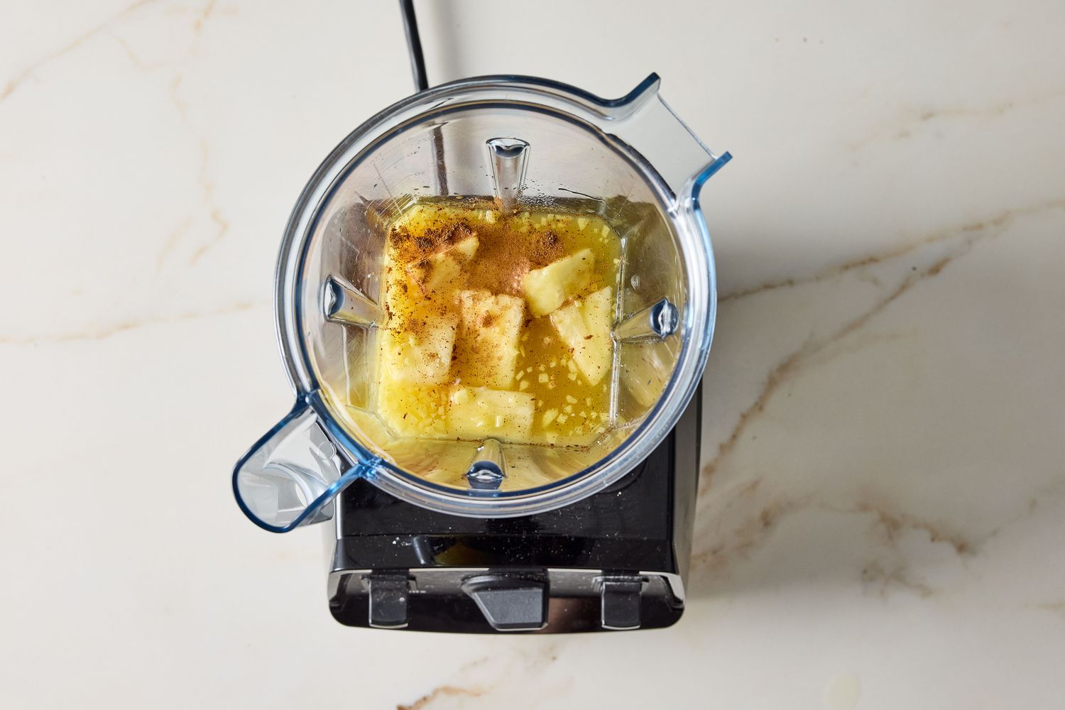 Blender with pineapple and ginger ingredients being blended