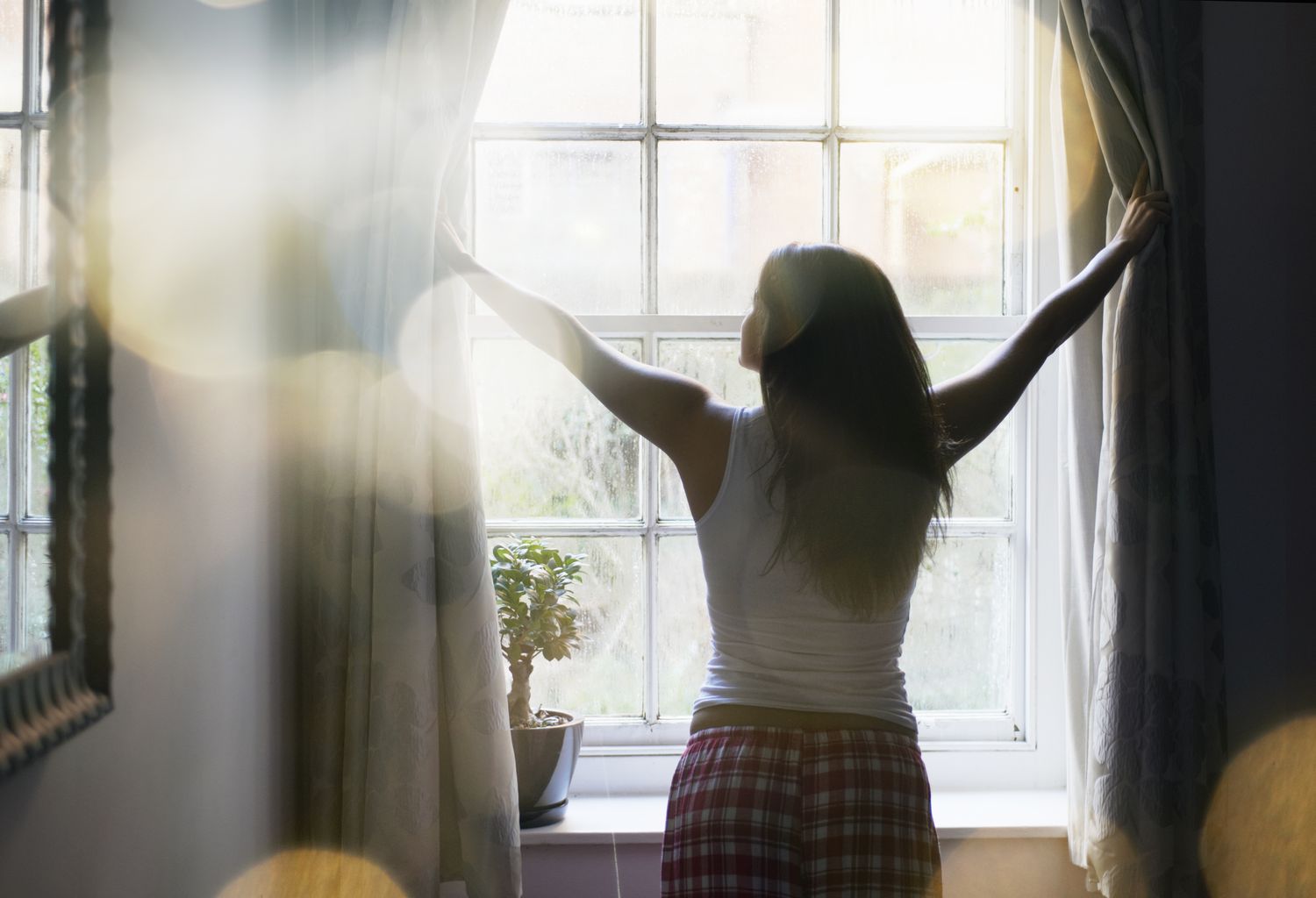 woman opening curtain in the morning