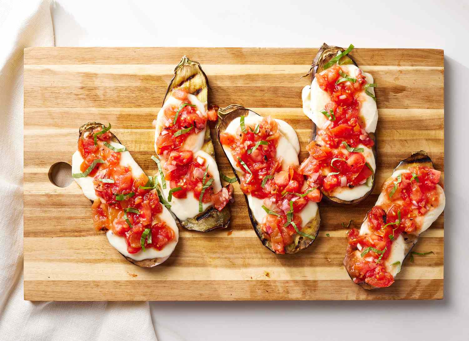 overhead view of sliced eggplant, cheese and tomatoes on a cutting board