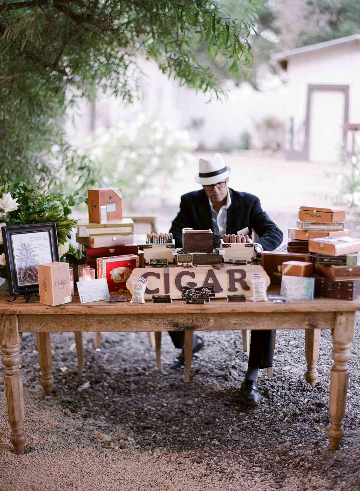man sitting behind wooden table at reception for cigar booth