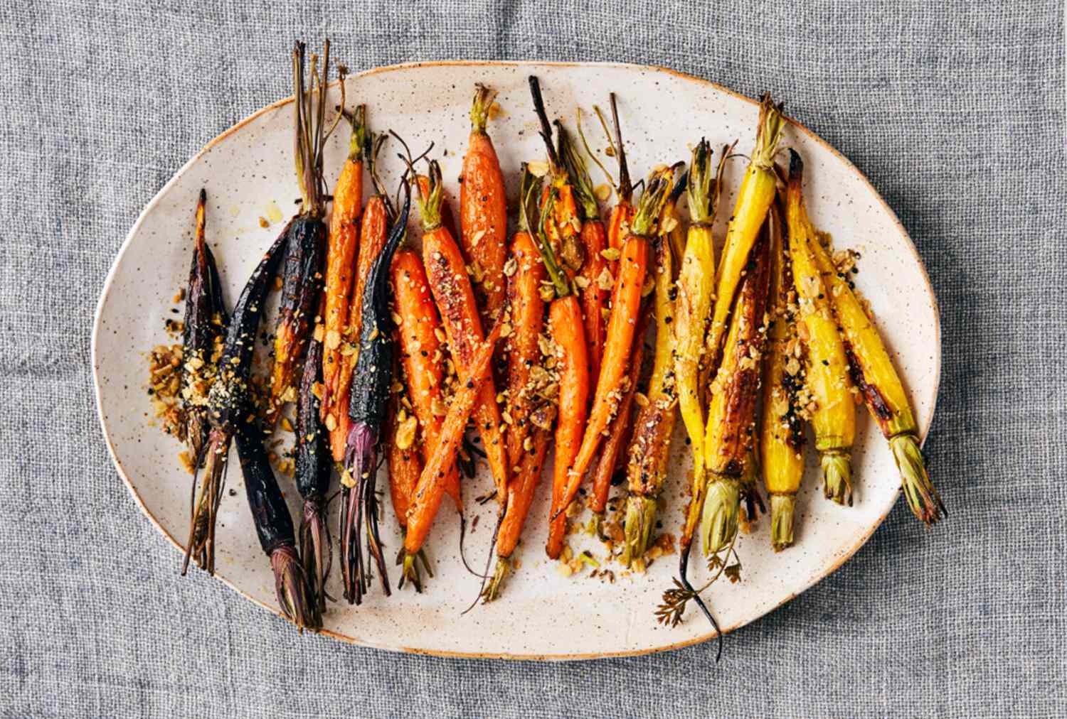Platter of roasted carrots with seasonings on a grey background