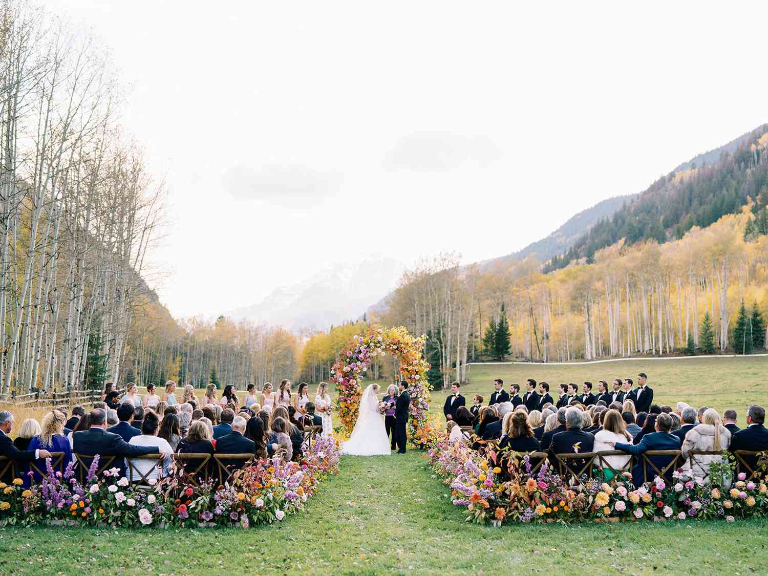 outdoor wedding ceremony with colorful floral archway