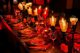 A long dining table set with plates glassware and lit candles creating an elegant and intimate atmosphere