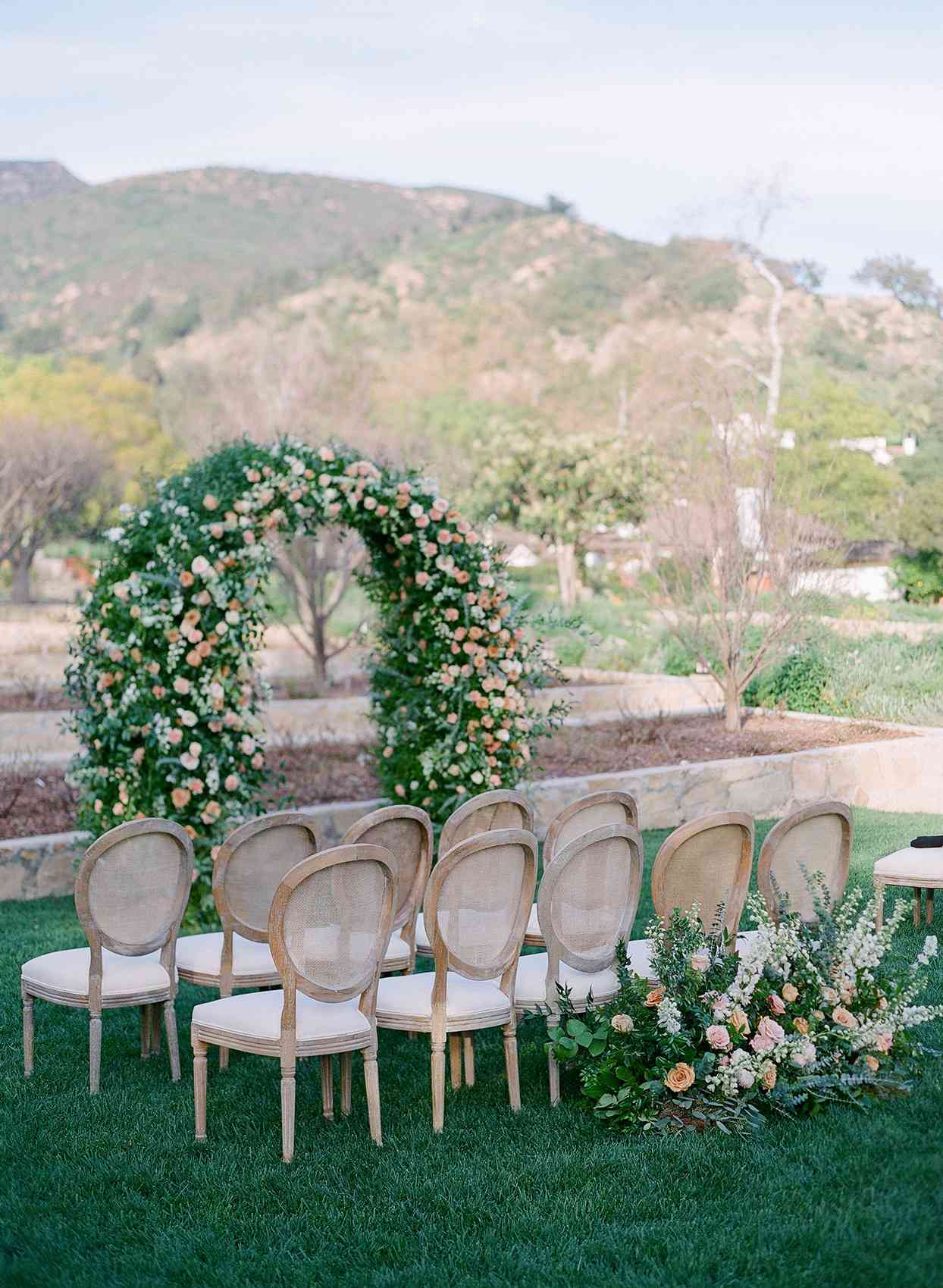 wooden chairs set up for outdoor ceremony with mountain backdrop
