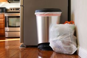 A full garbage bag sitting on the floor in a kitchen