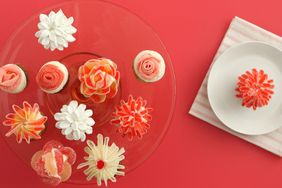 A selection of floralthemed cupcakes displayed on a plate and next to a single cupcake on a separate small dish