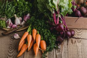 Root vegetables including carrots beets and garlic on a wooden table
