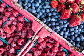 A market display of fresh raspberries blueberries and strawberries in cartons