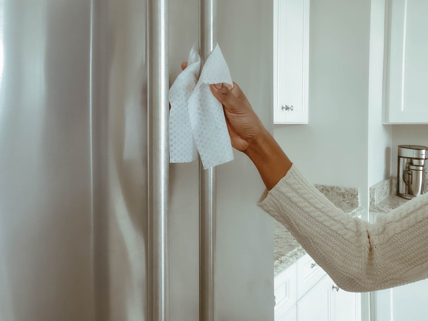 A person cleaning a refrigerator handle with a cloth