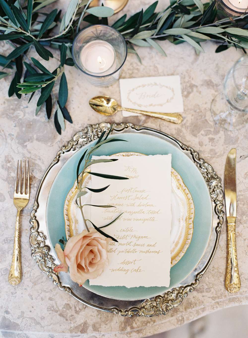 gold and silver place setting with a pink rose atop plate