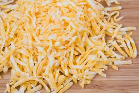 Shredded Colby and Monterey Jack cheese on a wood cutting board.