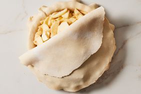 sliced apples in a pie crust with partially covered top layer of pie crust