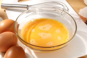 Liquid eggs in a bowl with a whisk. 