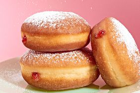 strawberry jam-filled doughnut getting sprinkled with powdered sugar