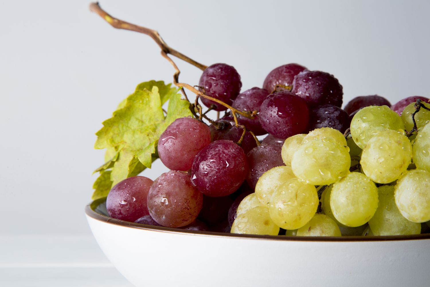 red and green grapes on white wooden table