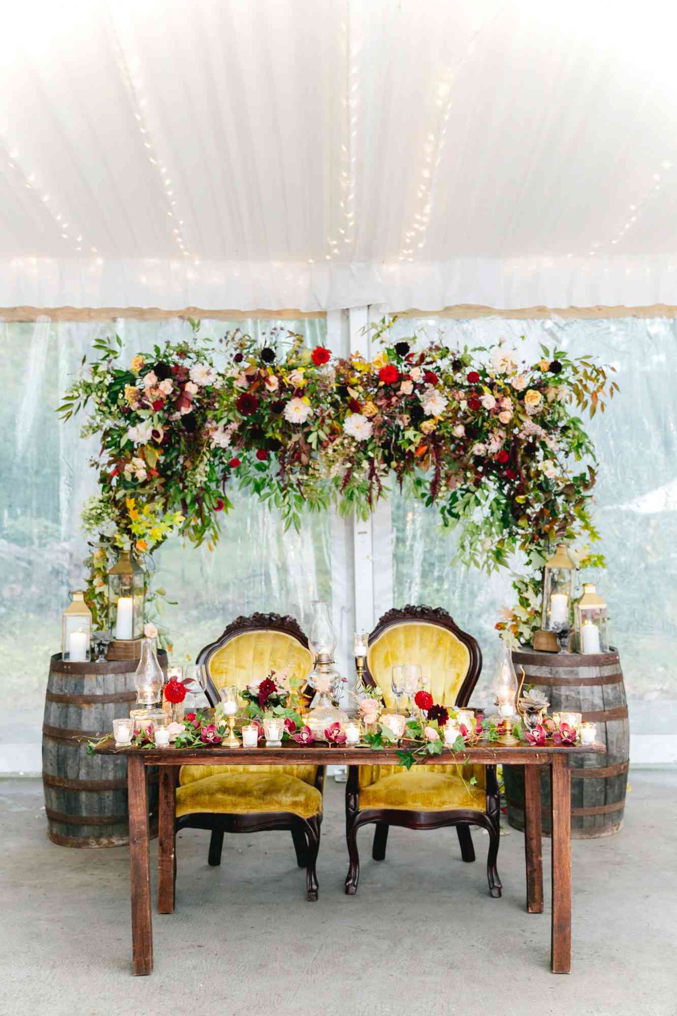 sweetheart table floral arch yellow chairs and barrels