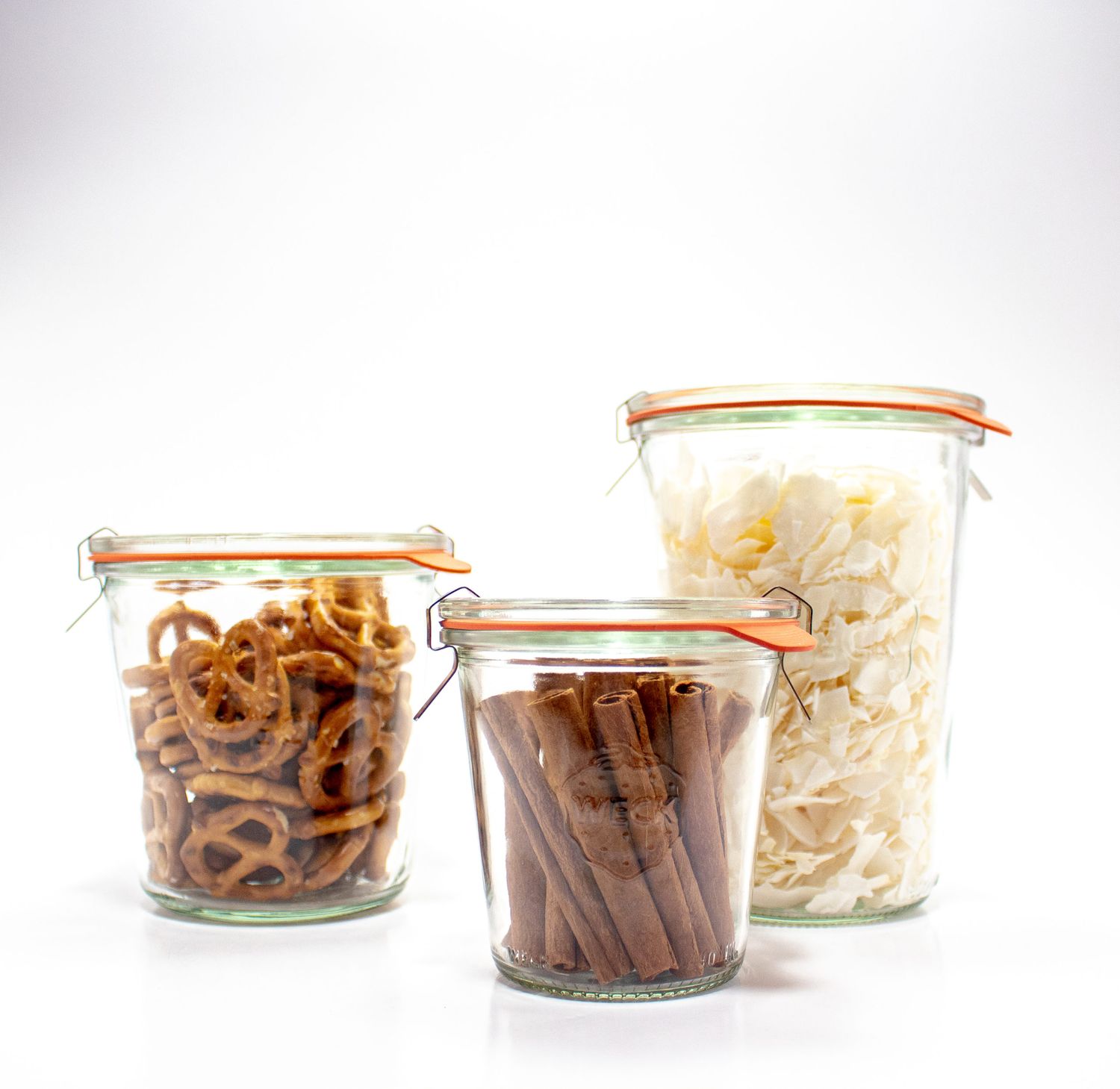 Three glass jars containing pretzels cinnamon sticks and a dried food product