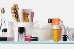 Various personal care items including bottles nail polish a hairbrush and prescription containers on a bathroom counter