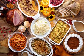 Traditional Thanksgiving dinner with a roasted turkey sliced ham side dishes and a pumpkin pie on a table