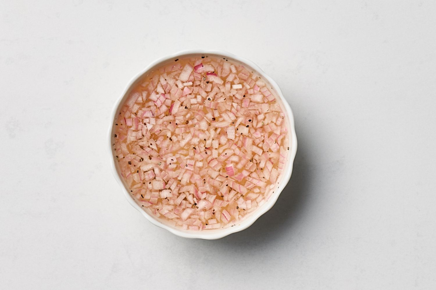 A small bowl containing a minced onion mixture likely champagne mignonette sauce
