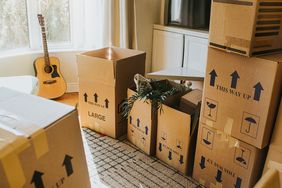Packed moving boxes and a guitar in a room