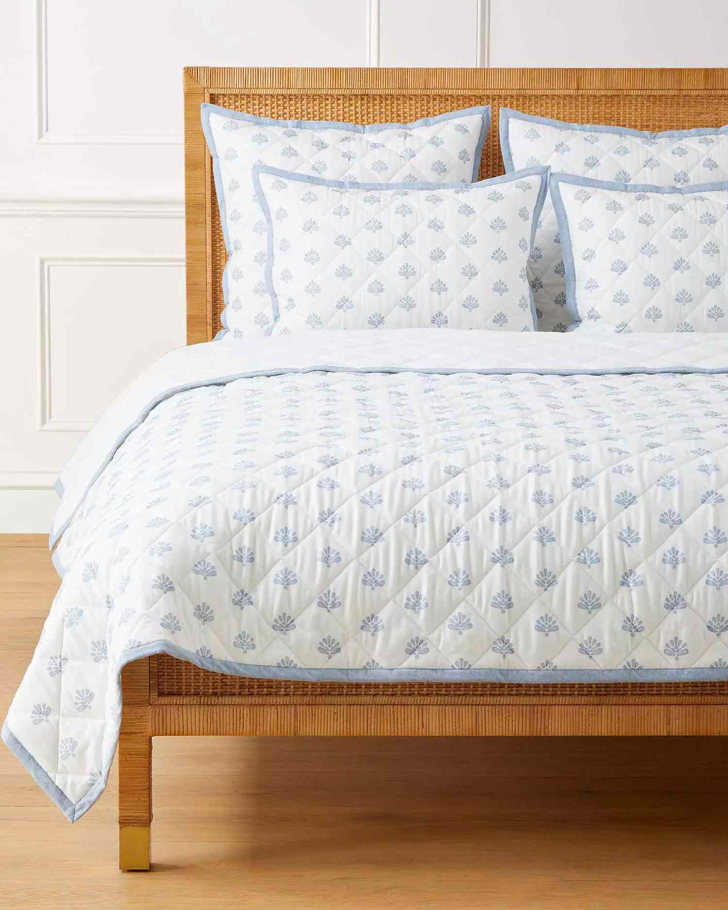 A bed with a blue and white quilt