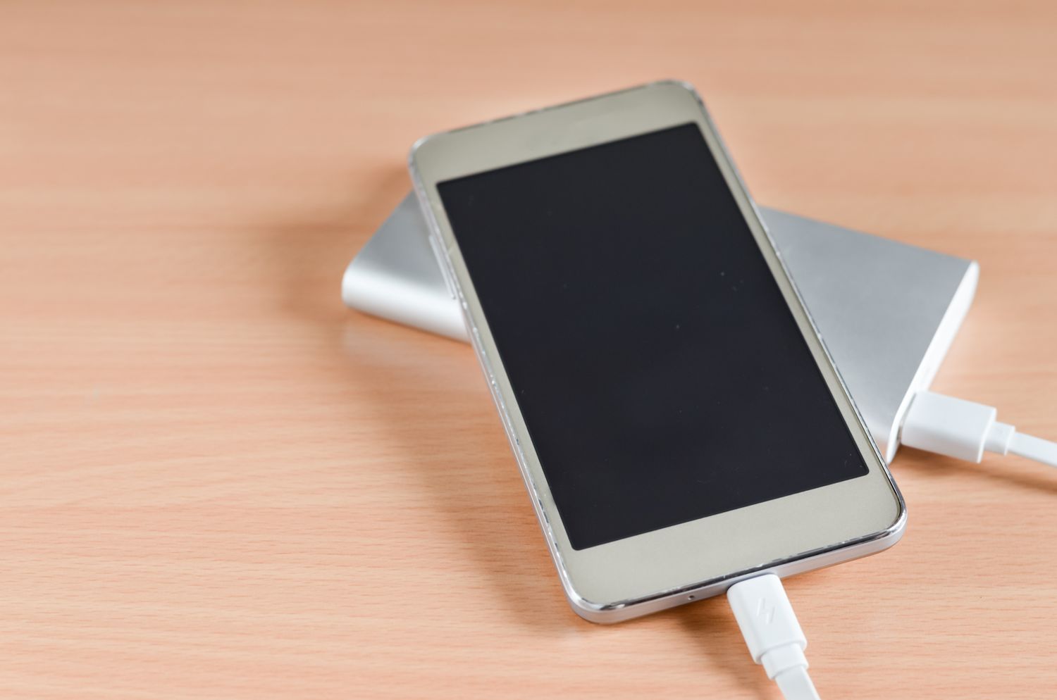 Smartphone charging on a power bank placed on a wooden surface