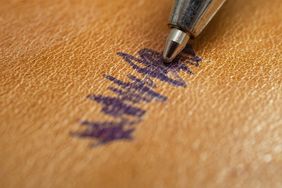 A pen leaving a stain on a leather surface