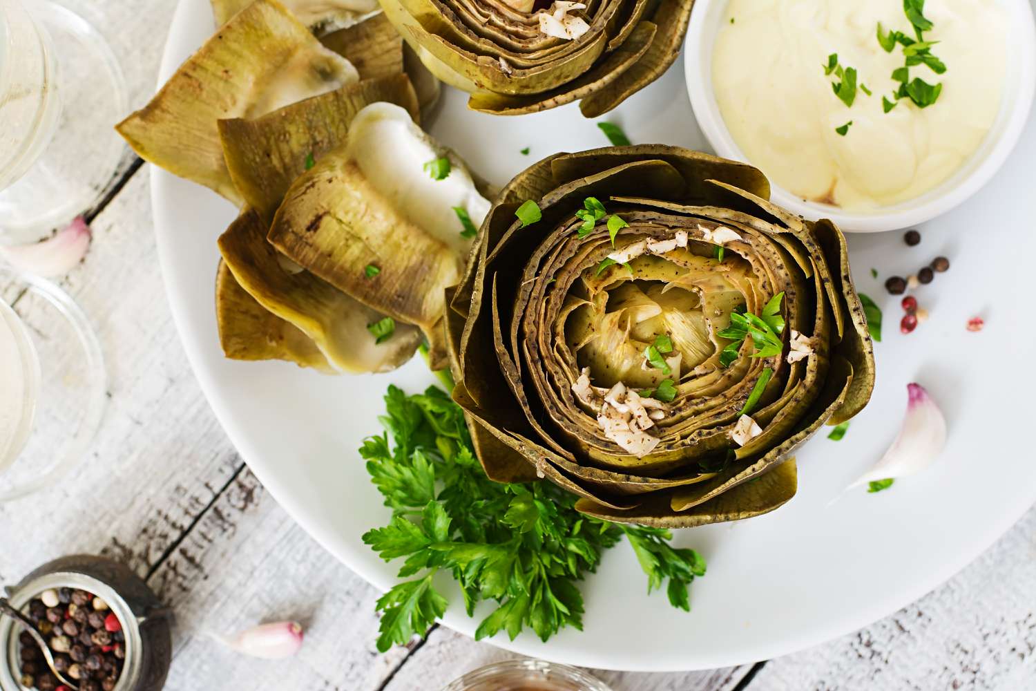 steamed artichoke with sauce on white plate