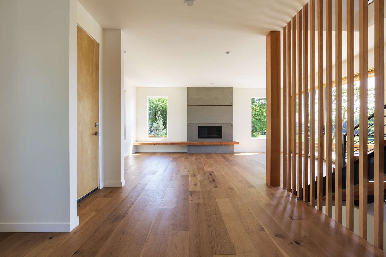 Modern living space with wooden floors a central fireplace and large windows letting in natural light