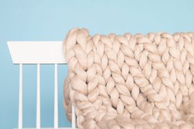 completed arm knit blanket folded over white bench