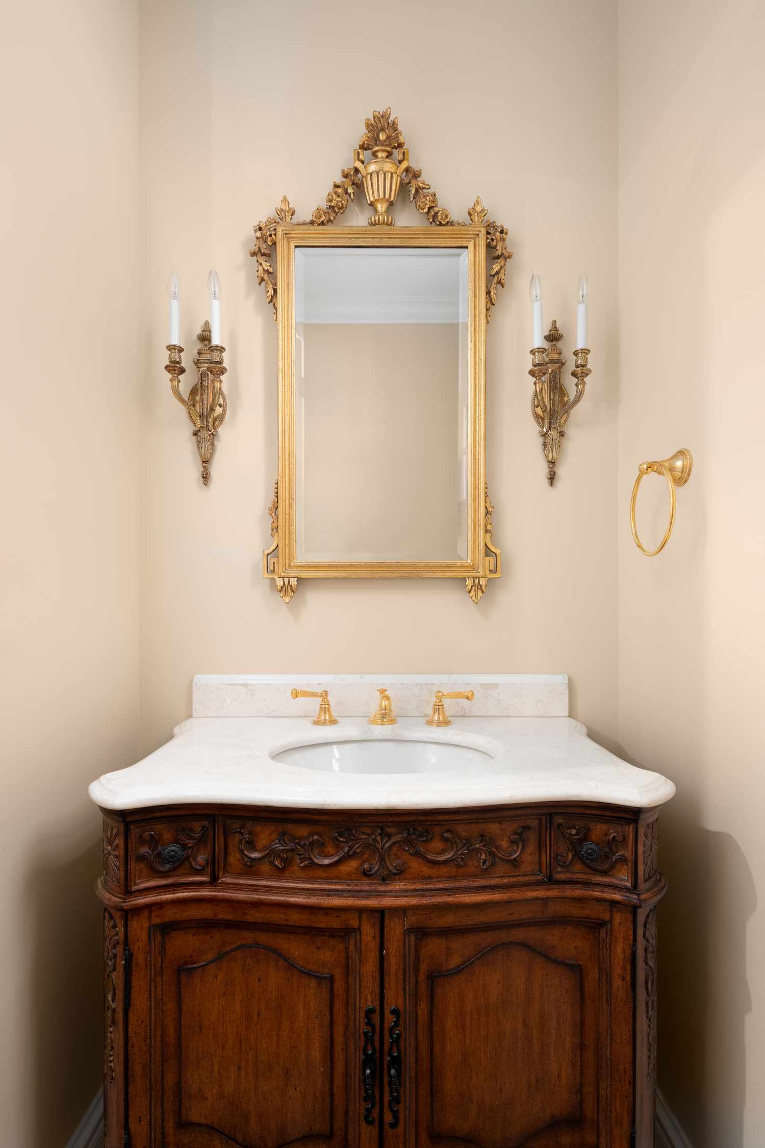 A detailed bathroom vanity with ornate mirror and fixtures includes a wooden cabinet and marble countertop